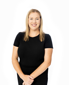 Smiling woman in black shirt with blonde hair standing confidently